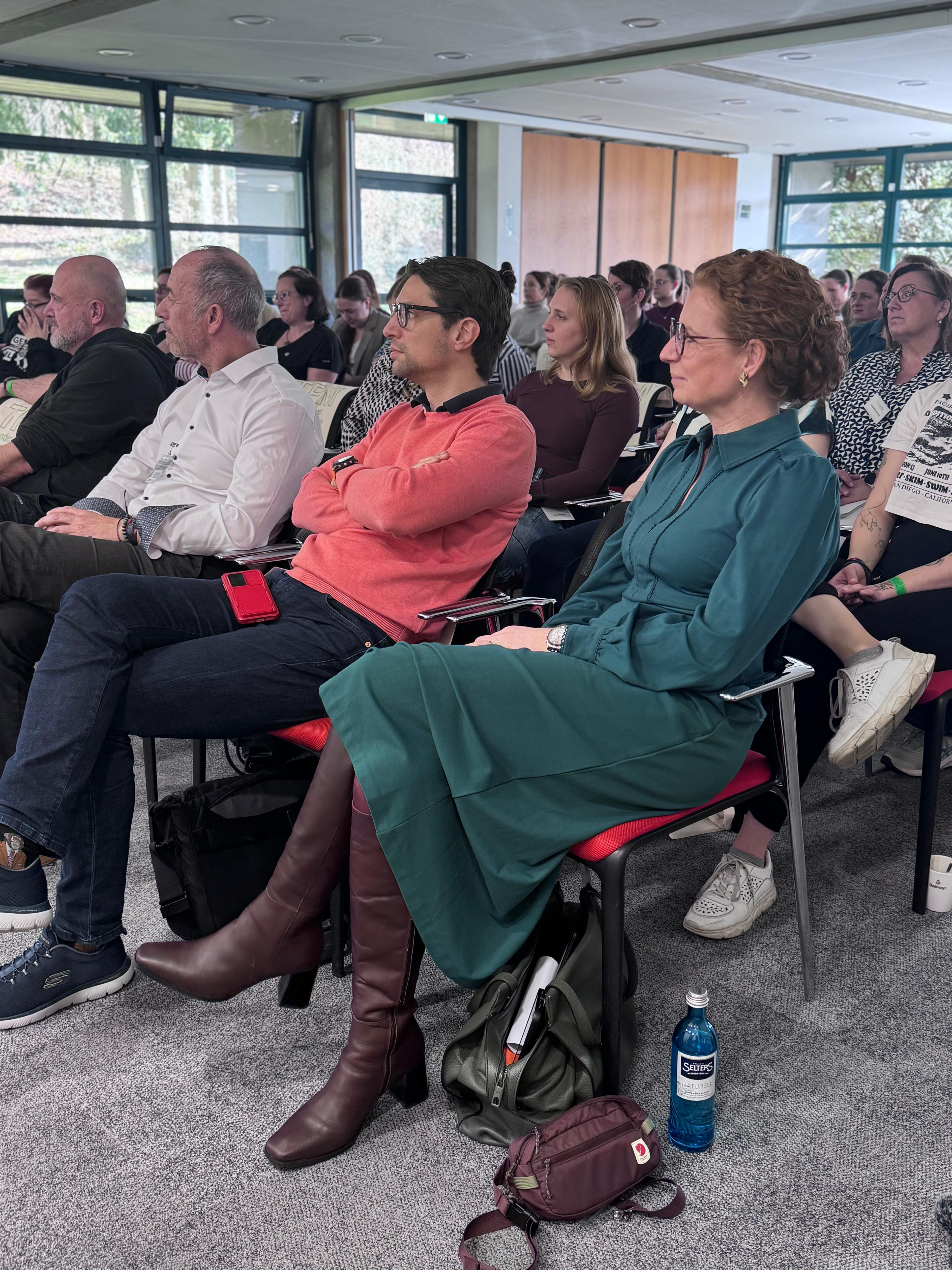 Teilnehmer sitzen aufmerksam bei einer Veranstaltung oder Konferenz im modernen Seminarraum
