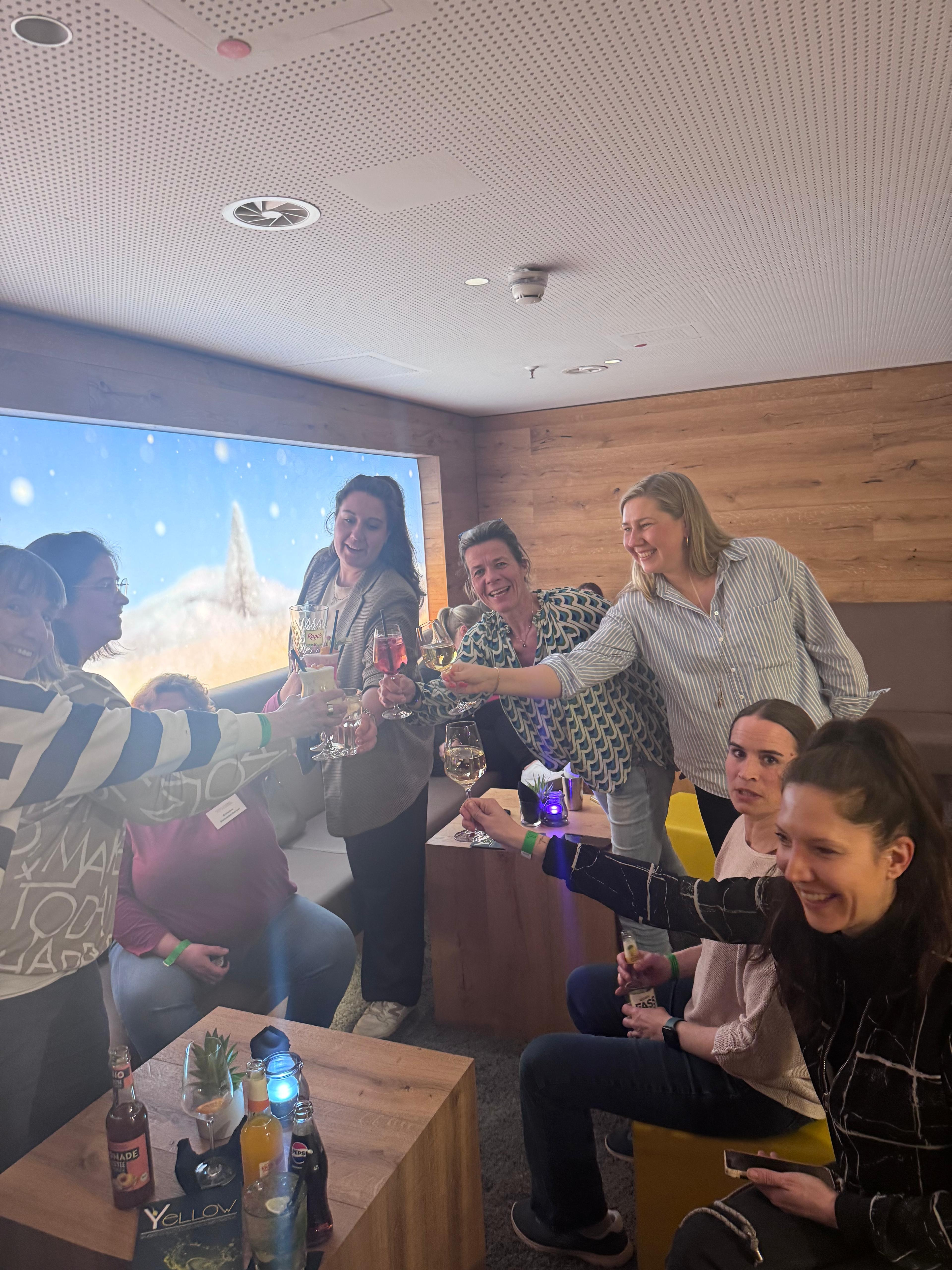 Gruppe von Frauen stößt in gemütlicher Lounge mit Getränken an
