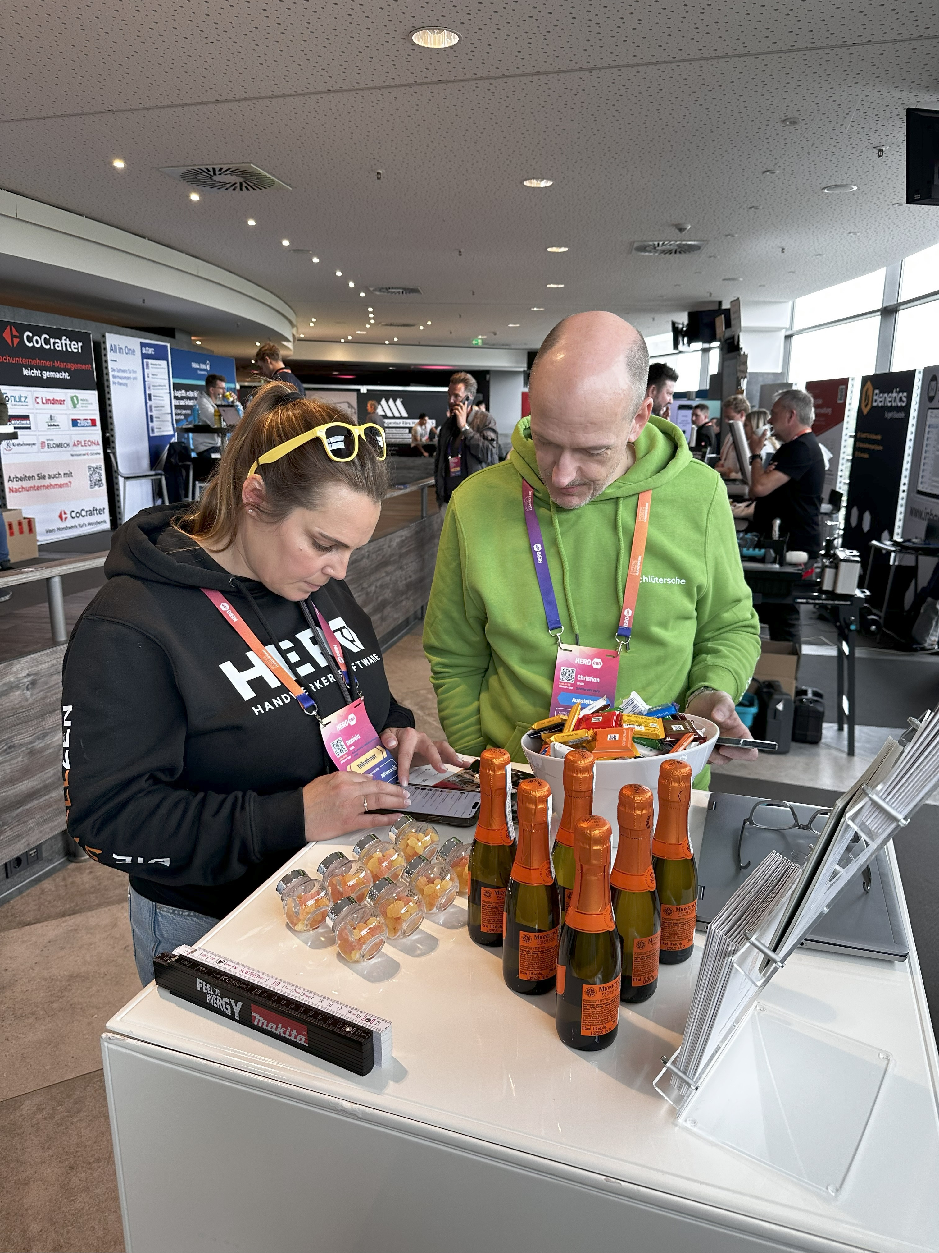 Besucher interagieren an einem Messestand auf einer Messe Besucher an einem Messestand mit Werbeartikeln und Getränken