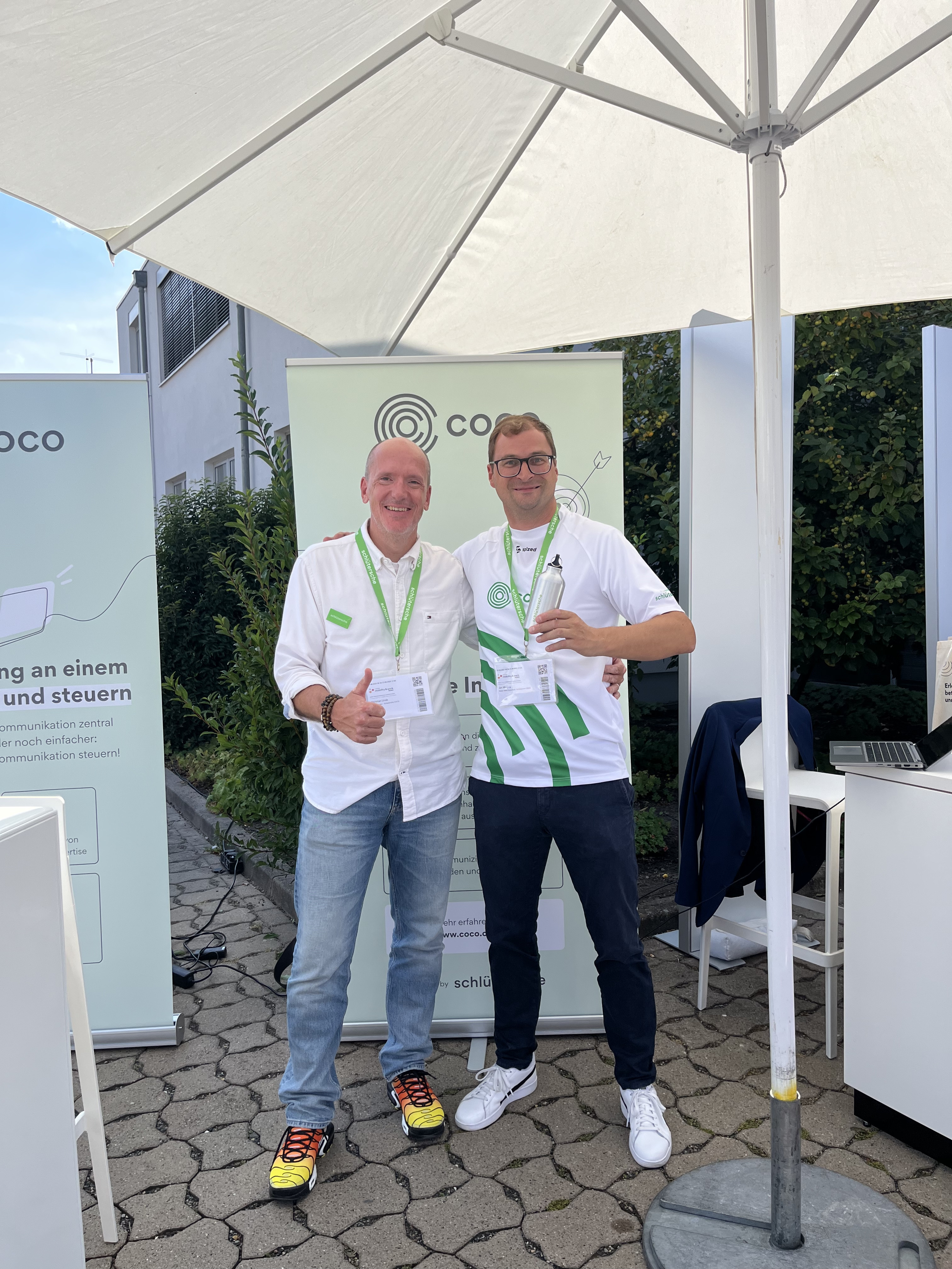 COCO Messestand mit zwei Personen bei einer Outdoor-Veranstaltung Zwei Personen am Messestand von COCO bei einer Outdoor-Veranstaltung