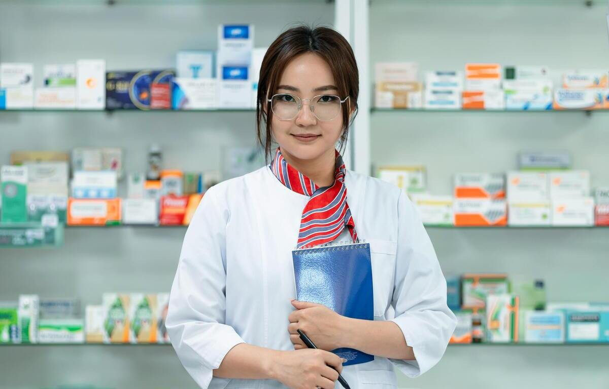 Junge Apothekerin in einer Apotheke mit Medikamenten im Hintergrund