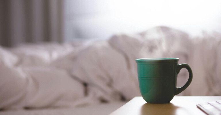 Teetasse auf Nachttisch im Schlafzimmer Teetasse auf einem Nachttisch vor einem unscharfen Hintergrund