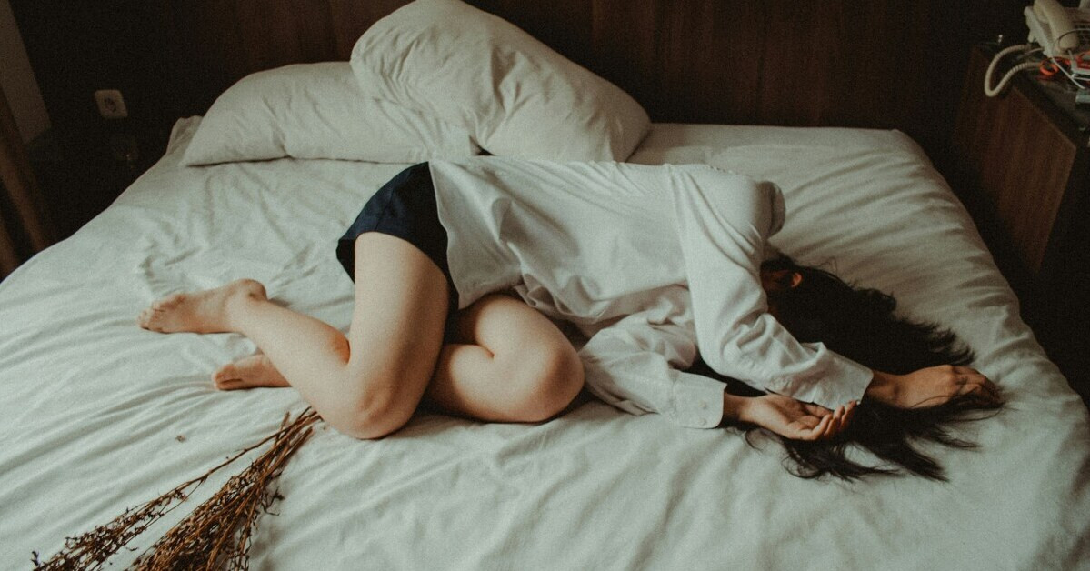 Frau mit Regelschmerzen liegend auf dem Bett Frau mit Regelschmerzen liegt auf dem Bett