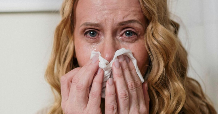 Frau mit Taschentuch zeigt typische Symptome von Pollenallergie