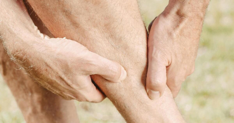 Muskelschmerz am Bein – Symptome und Behandlung Mann hält sich das schmerzende Bein wegen Muskelschmerz
