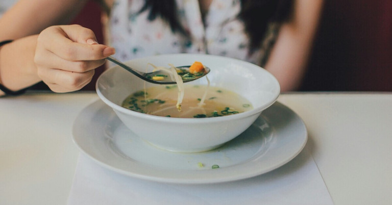 Frische Suppe mit Gemüse in einer weißen Schale, Nahaufnahme
