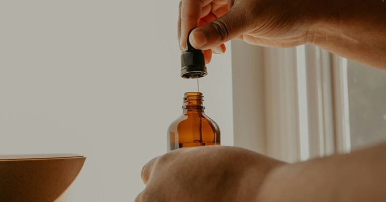 Ätherisches Öl in brauner Glasflasche mit Pipette Braune Glasflasche mit ätherischem Öl und Pipette in der Hand