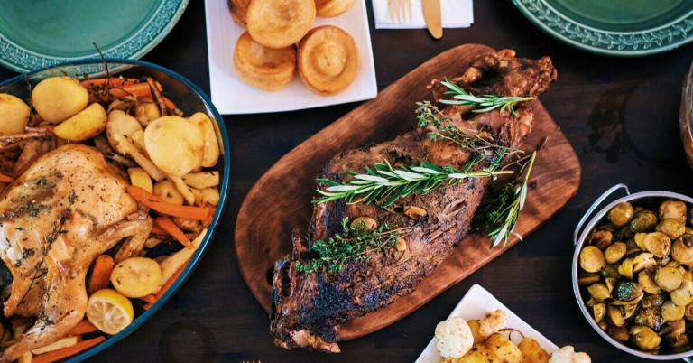 Festessen mit gebratenem Fleisch, Rosmarin und Beilagen wie Gemüse und Yorkshire Pudding auf einem festlich gedeckten Tisch