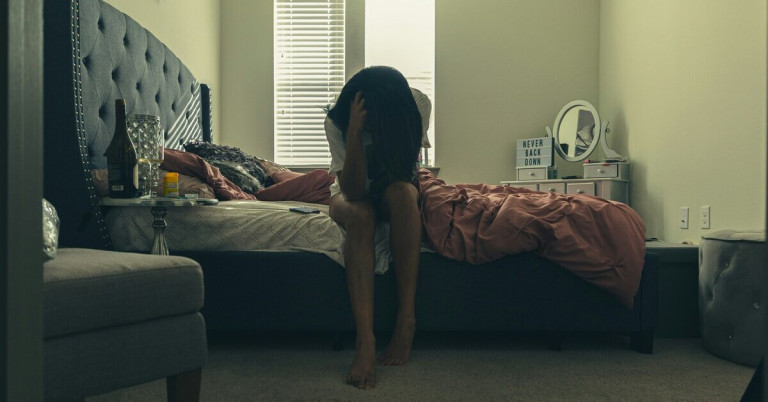 Frau mit Depression sitzt auf dem Bett – Symbolbild für depressive Verstimmung Frau sitzt auf dem Bett und wirkt depressiv, Symbolbild für Depression bei Frauen