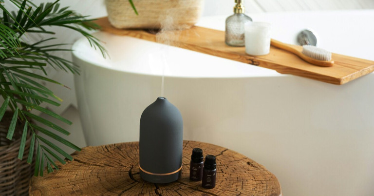 Luftbefeuchter mit ätherischen Ölen für ein angenehmes Raumklima im Badezimmer Moderner Luftbefeuchter mit ätherischen Ölen auf Holztisch im Badezimmer