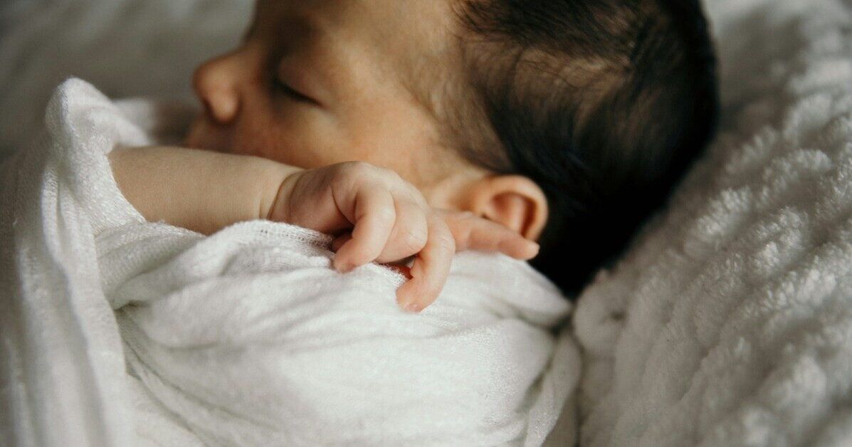 Fieber messen bei einem Baby – Nahaufnahme eines Babys in einer weißen Decke