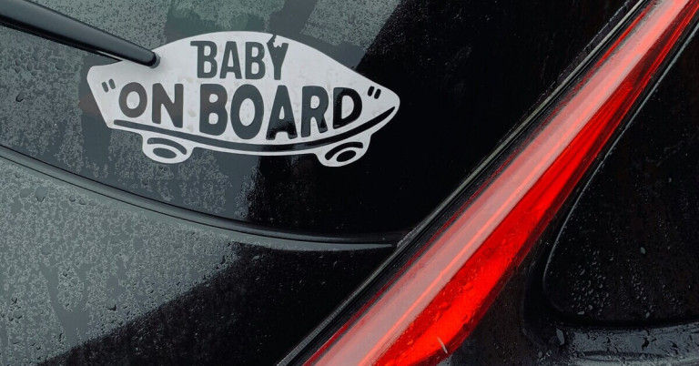 Baby im Auto: Sicherheitshinweis mit 'Baby on Board'-Aufkleber am Auto Baby im Auto – Aufkleber 'Baby on Board' auf Heckscheibe eines Fahrzeugs