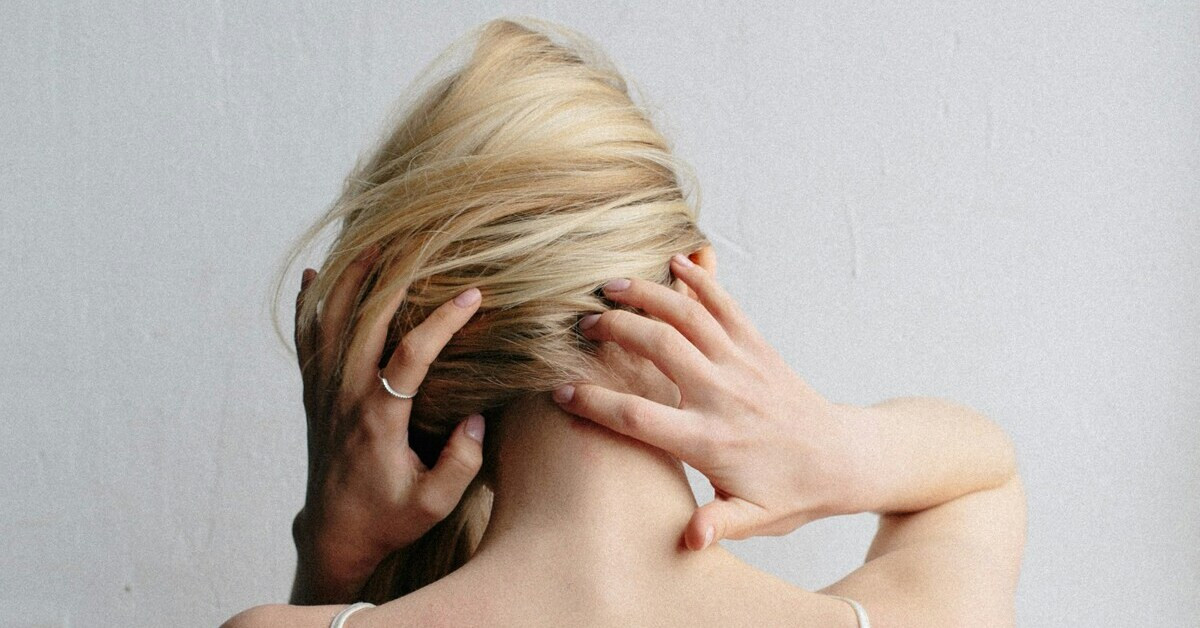 Frau hält sich den Nacken wegen Nackenschmerzen