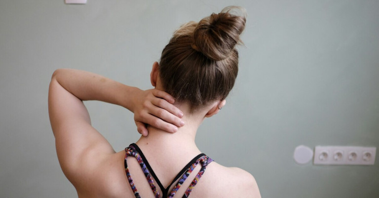 Frau hält sich den Nacken wegen Schmerzen im Hals- und Nackenbereich