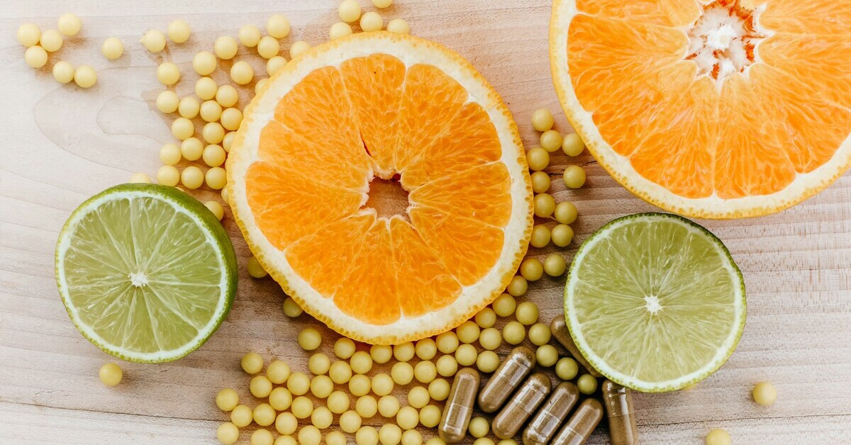 Obst und Vitamine: Frische Orangenscheiben, Limetten und Vitaminpräparate auf einem Holztisch