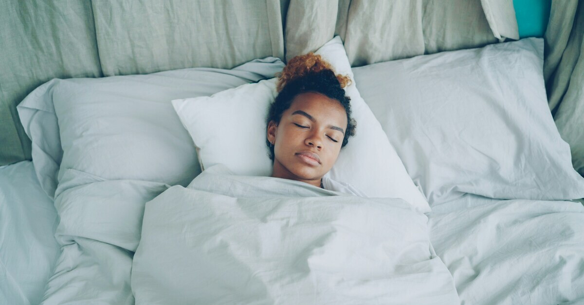 Frau schläft mit extra Kissen im Bett