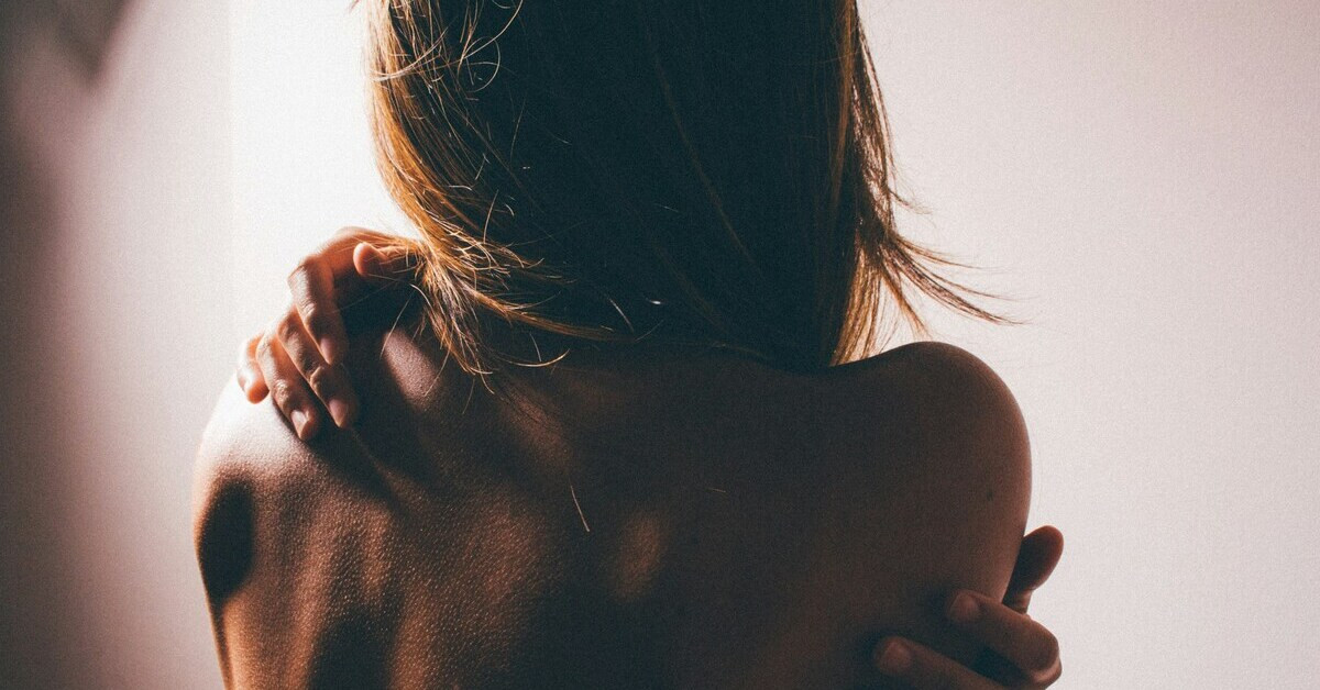 Frau kratzt sich am Rücken aufgrund juckender Haut