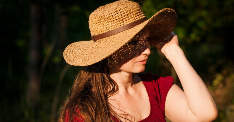 Sonnenschutz durch Strohhut – Frau genießt die Sonne Frau mit Strohhut als Sonnenschutz im Sommer
