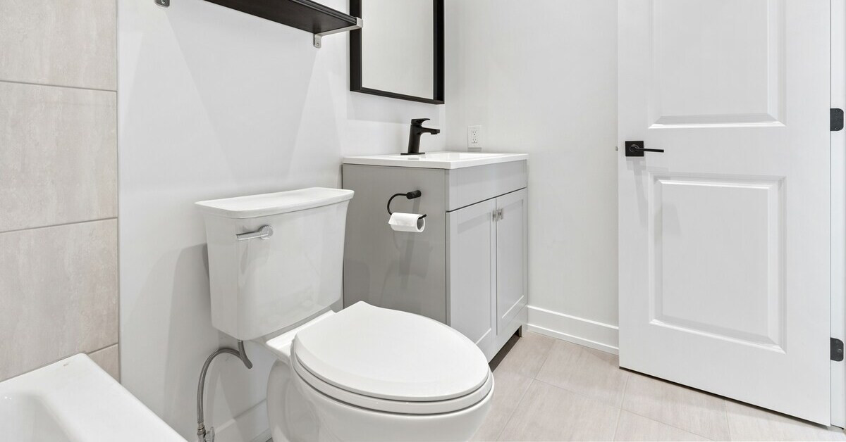 Modernes Badezimmer mit Toilette, Waschbecken und hellen Fliesen