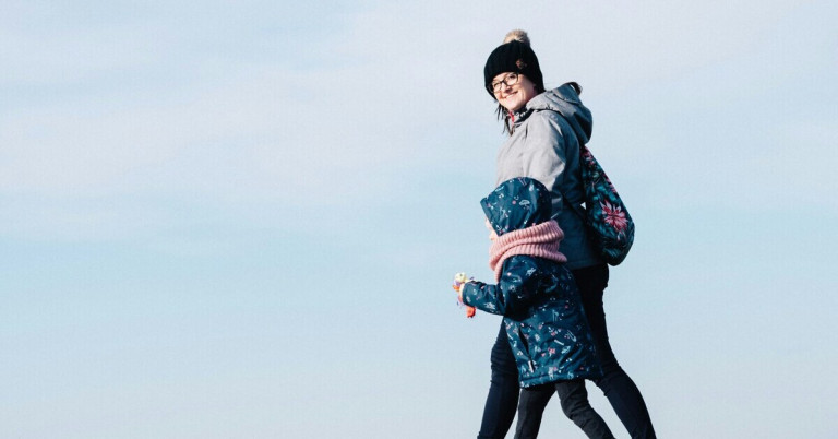 Zwei Personen beim Spaziergang an einem klaren Tag, beide warm angezogen