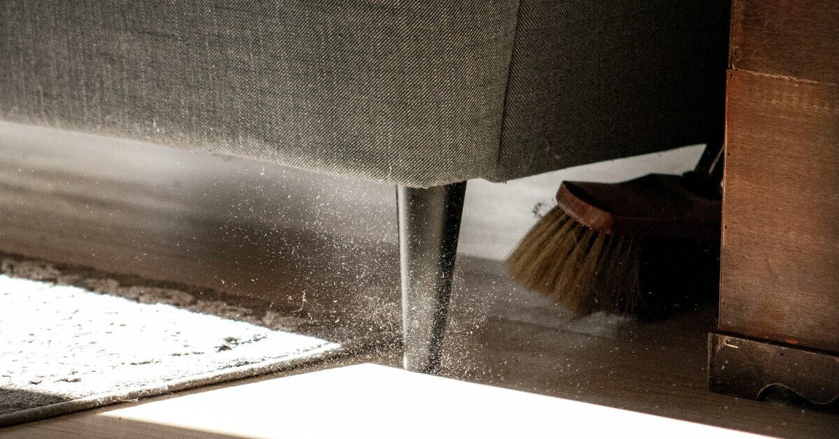 Staub unter einem Sofa beim Fegen mit einer Bürste