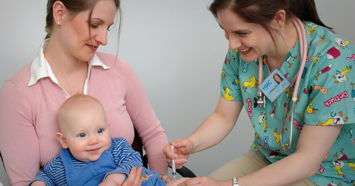 Baby wird von einer Ärztin geimpft, sitzt auf dem Schoß der Mutter