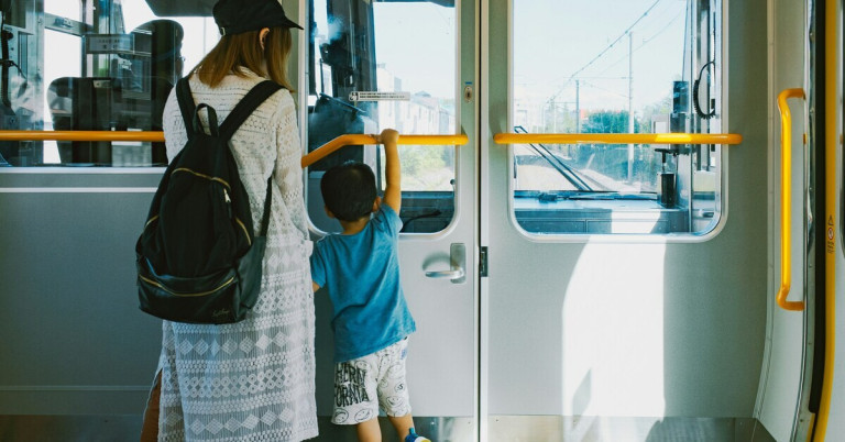 Mutter und Kind in einer Bahn, beide stehen an der Tür und schauen hinaus