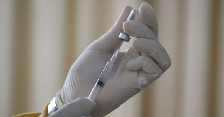 Spritze aufziehen – Vorbereitung einer Injektion mit Medikament Hand mit Handschuh zieht eine Spritze aus einem Medikamentenfläschchen auf