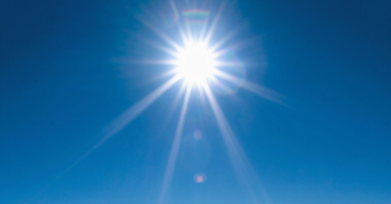 Strahlende Sonne mit intensivem Sonnenlicht am Himmel Strahlende Sonne am blauen Himmel