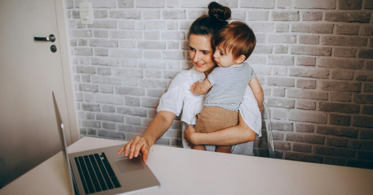 Mama arbeitet – Mutter mit Kind am Laptop im Homeoffice Mama arbeitet am Laptop und hält ihr Kind auf dem Arm