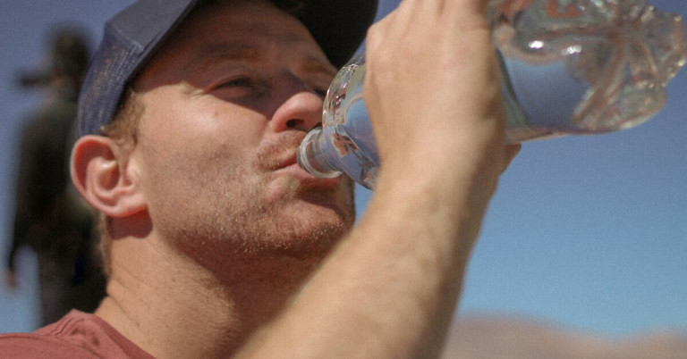 Trinken bei Hitze – Wasser trinken zur Abkühlung und Hydration an heißen Tagen Mann trinkt Wasser bei Hitze, um sich zu erfrischen und hydratisiert zu bleiben