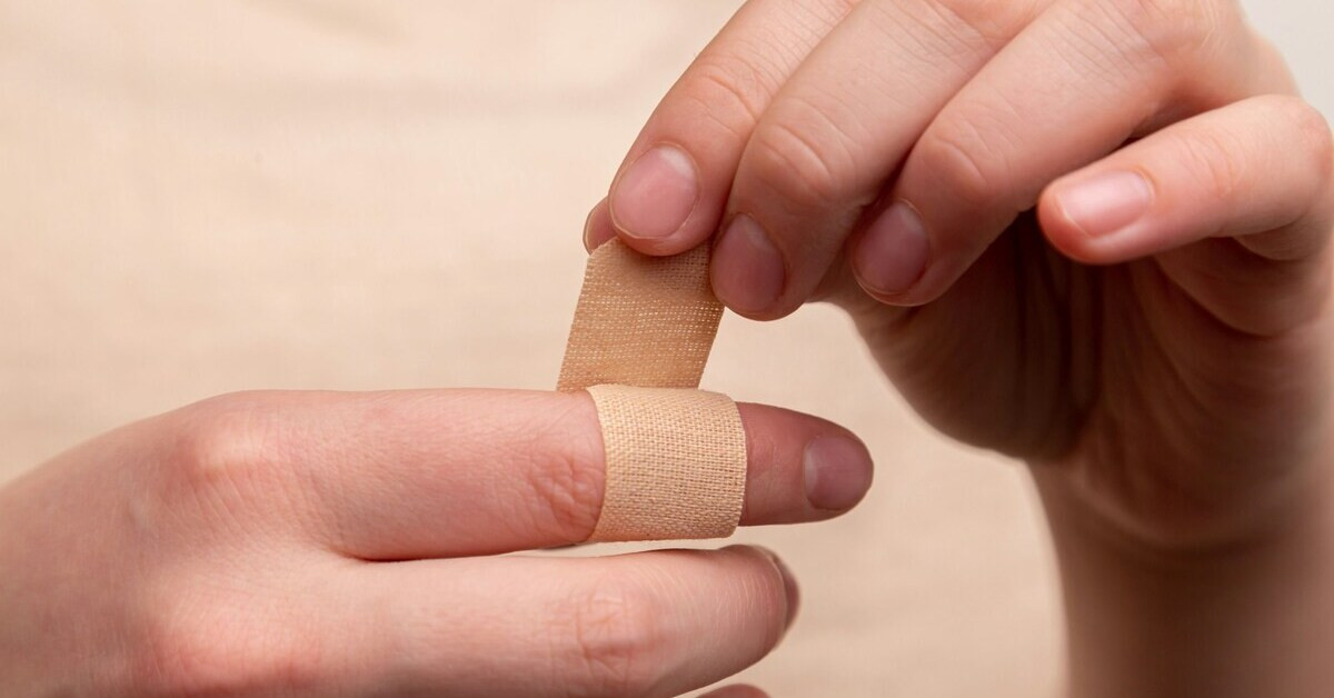 Nahaufnahme: Pflaster anbringen auf einem Finger, Schritt-für-Schritt-Anleitung zur Wundversorgung