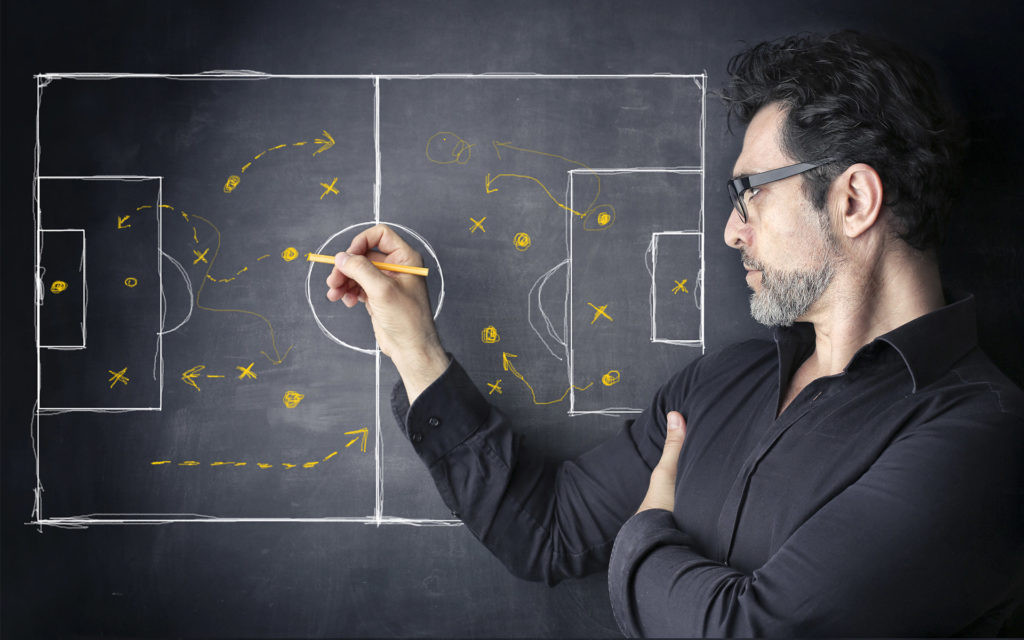 Fußballtrainer zeichnet Strategie auf Taktiktafel