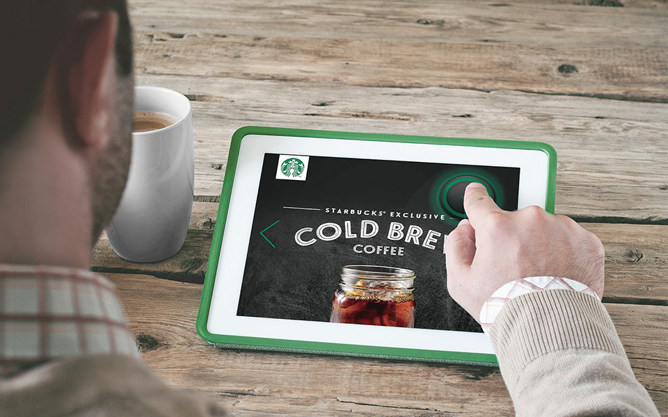 Person nutzt PiTouch-Tablet mit Starbucks Cold Brew Anzeige