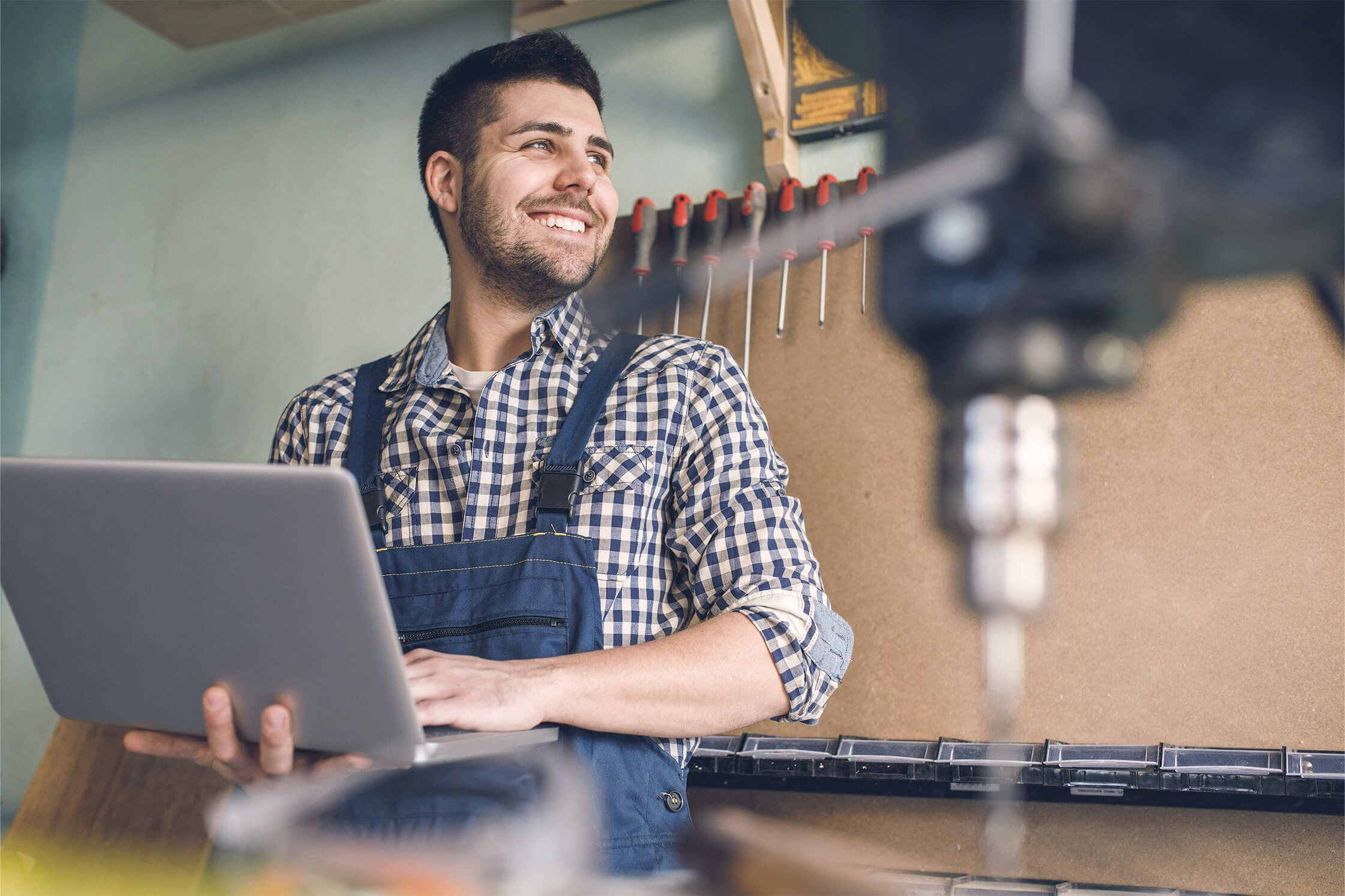 Handwerker mit Laptop in einer Werkstatt
