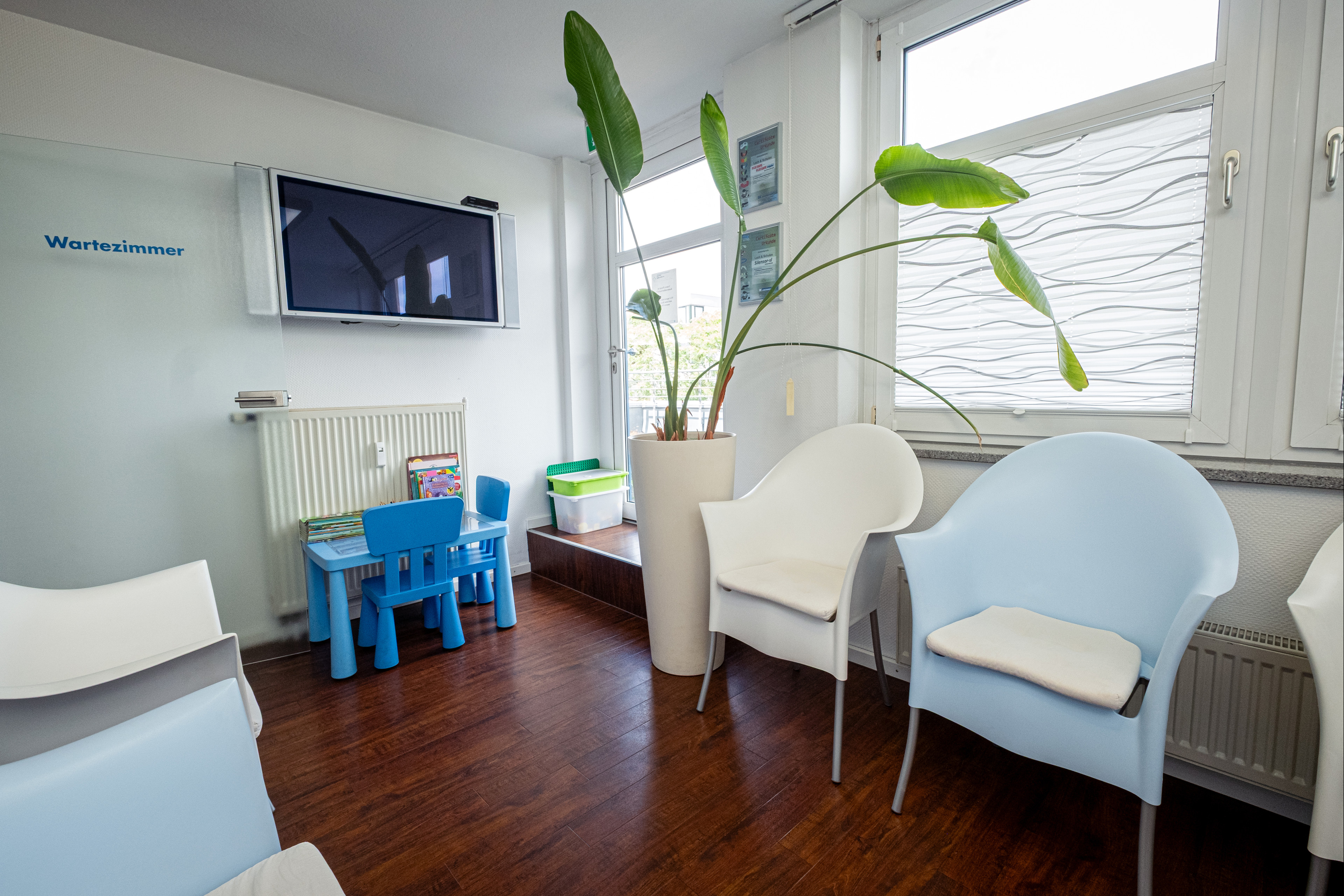 Wartezimmer mit moderner Einrichtung, Kinderspielecke und Pflanzen Modernes Wartezimmer mit Sitzgelegenheiten, Kinderspielecke und großen Pflanzen