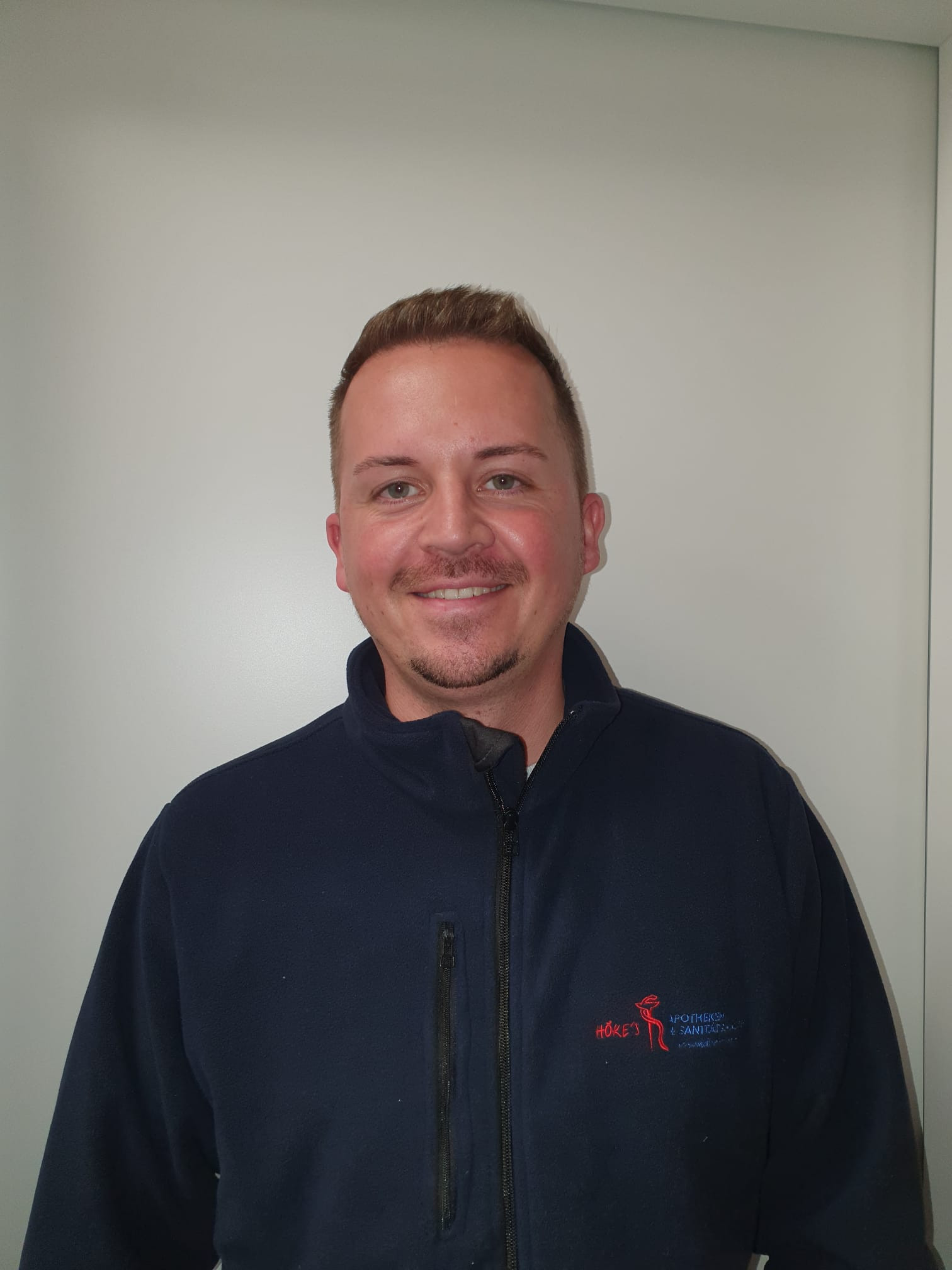 Tobias Franke im Arbeitsoutfit mit Jacke der Höker Apotheke