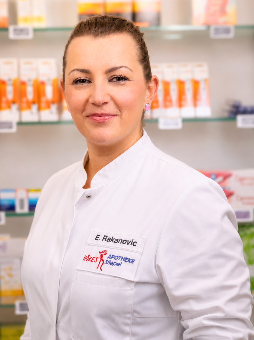 E. Rakanovic in der Höke's Apotheke Siepel, Mitarbeiterin im weißen Kittel vor Apothekenregal
