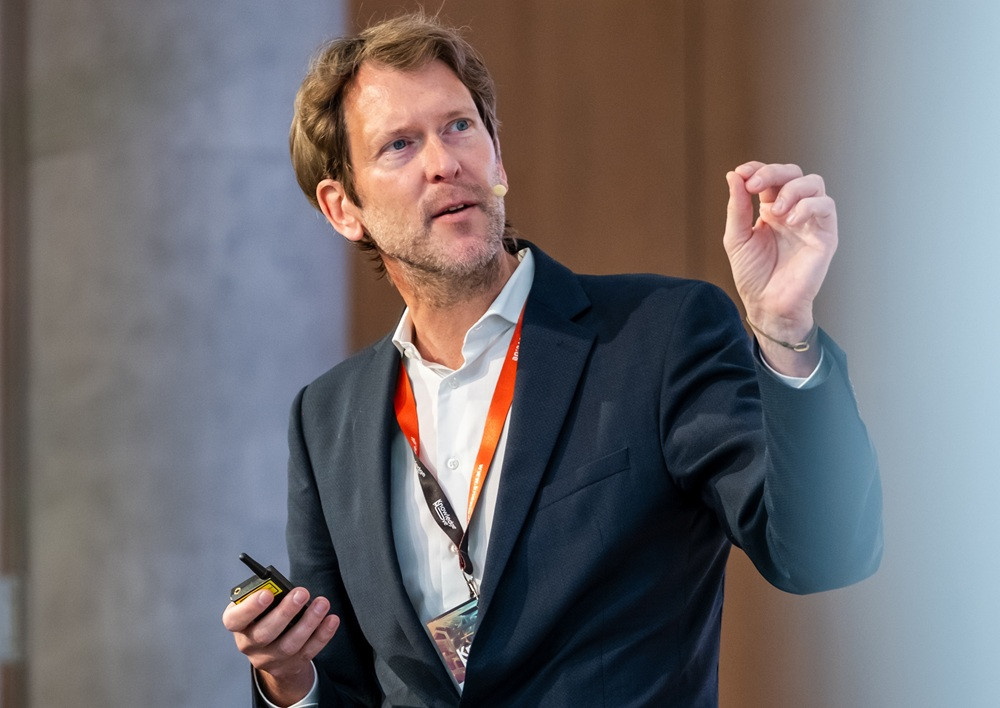 Präsentation von Person mit Mikrofon und Namensschild Person hält eine Präsentation mit Mikrofon und rotem Namensschild