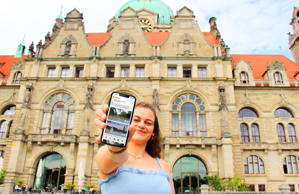 Frau mit Smartphone vor einem historischen Rathausgebäude Frau zeigt Smartphone vor einem historischen Rathausgebäude