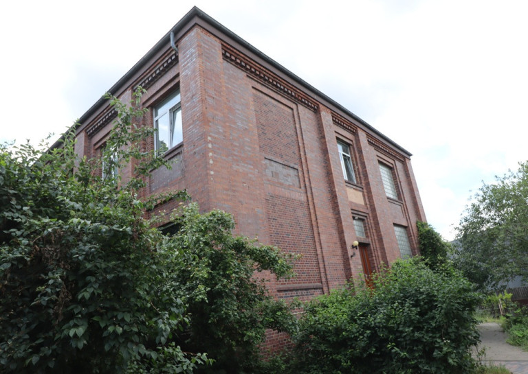 Backstein-Gebäude einer ehemaligen Kantine, umgeben von Büschen und Bäumen
