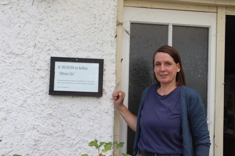 Person vor einem Erinnerungsort mit Schild 'kl. MUSEUM im Aufbau Offener Ort' an einer Hauswand
