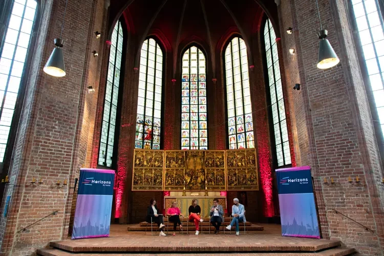 Podiumsdiskussion bei der Horizons-Konferenz in der Marktkirche mit beeindruckenden Kirchenfenstern und Altar im Hintergrund
