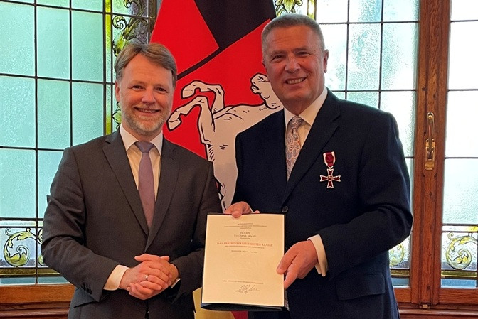 Thomas Mang bei der Verleihung des Bundesverdienstkreuzes, Ausschnitt, mit Urkunde und Auszeichnung