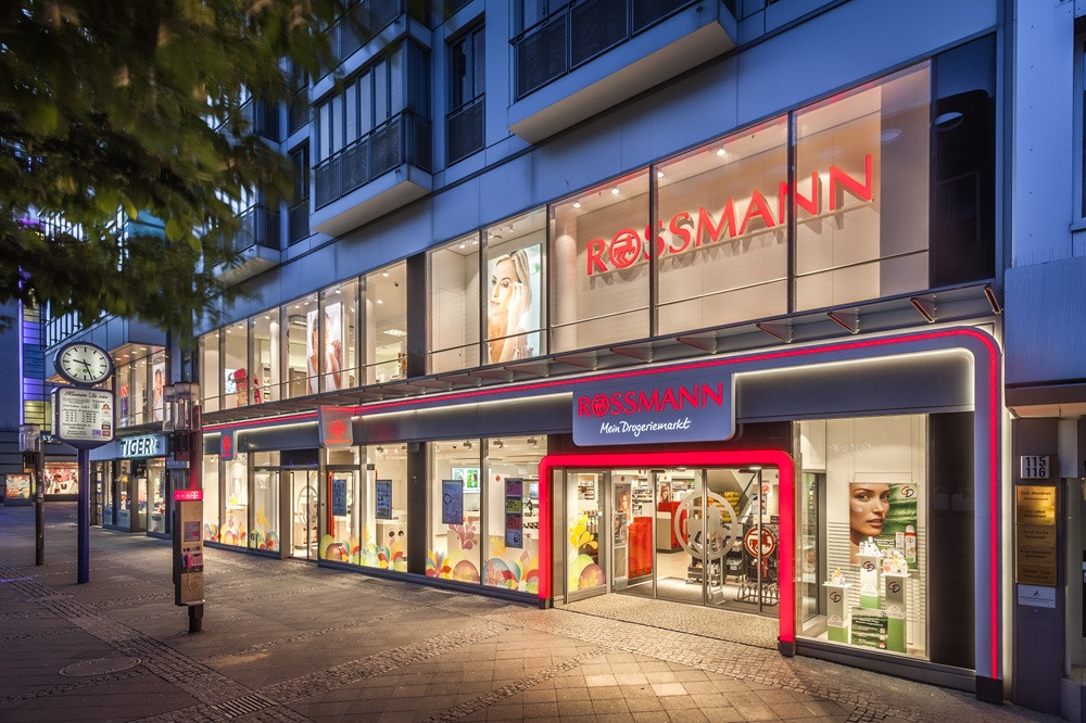 Rossmann Filiale von außen am Abend, beleuchtetes Geschäft mit Logo und Eingang
