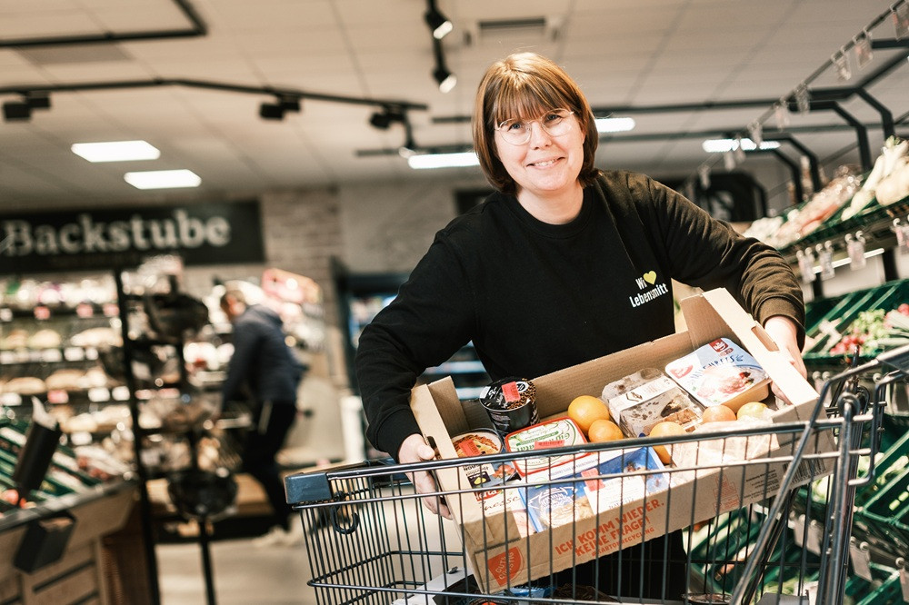Mitarbeiterin mit Lebensmittelkarton im Supermarkt – aufmacher-rahmen-slider-web