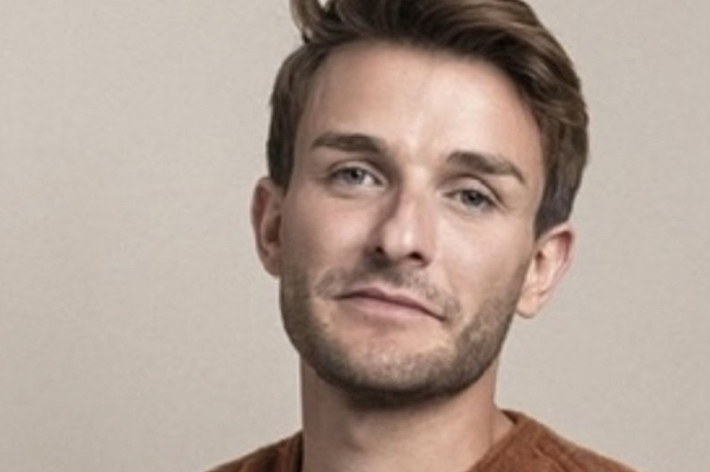 Porträt eines jungen Mannes mit braunen Haaren vor neutralem Hintergrund