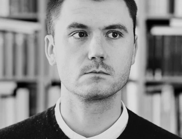 Schwarzweiß-Porträt von Julius Schien vor einem Bücherregal, 1788