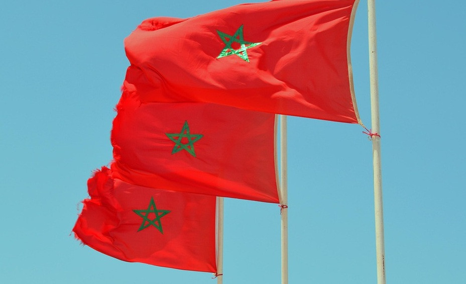 Drei marokkanische Flaggen wehen im Wind vor blauem Himmel in Marokko