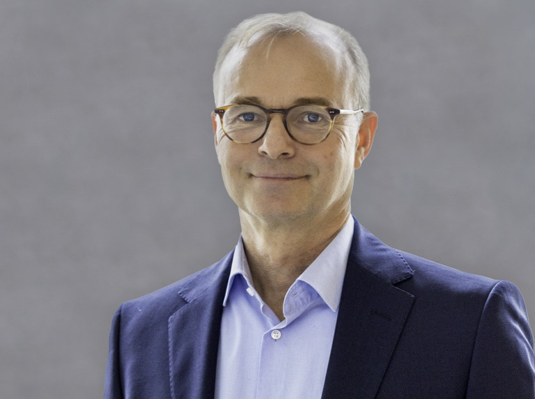 Michael Grosse im Business-Outfit Michael Grosse im Anzug vor grauem Hintergrund